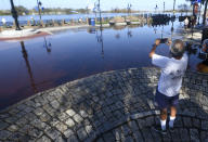 Godfrey Guerzon takes a picture of floodwaters from the Cape Fear River at the foot of Market St in downtown Wilmington, N.C., Sunday, September 23, 2018. The river is expected to crest on Monday night. (Matt Born/The Star-News via AP)