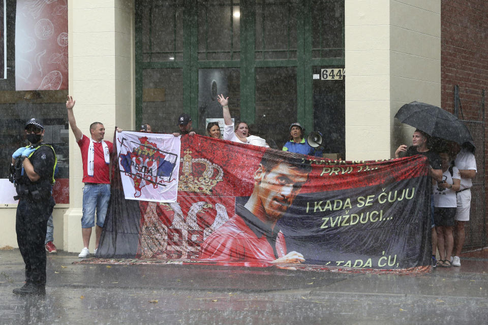 Protestors gather in a rain outside an immigration detention hotel where Serbia's Novak Djokovic is believed to stay, in Melbourne, Australia, Friday, Jan. 7, 2022. Locked in a dispute over his COVID-19 vaccination status, Djokovic was confined to the immigration detention hotel in Australia on Thursday as the No. 1 men's tennis player in the world awaited a court ruling on whether he can compete in the Australian Open later this month. (AP Photo/Hamish Blair)