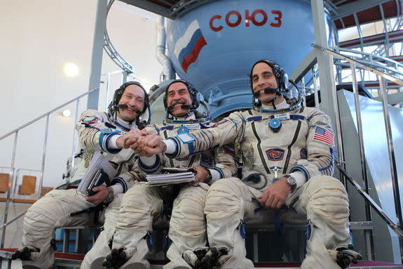 At the Gagarin Cosmonaut Training Center in Star City, Russia, Expedition 35/36 Flight Engineer Chris Cassidy (right), Soyuz Commander Pavel Vinogradov (center) and Flight Engineer Alexander Misurkin clasp hands for photographers prior to the s