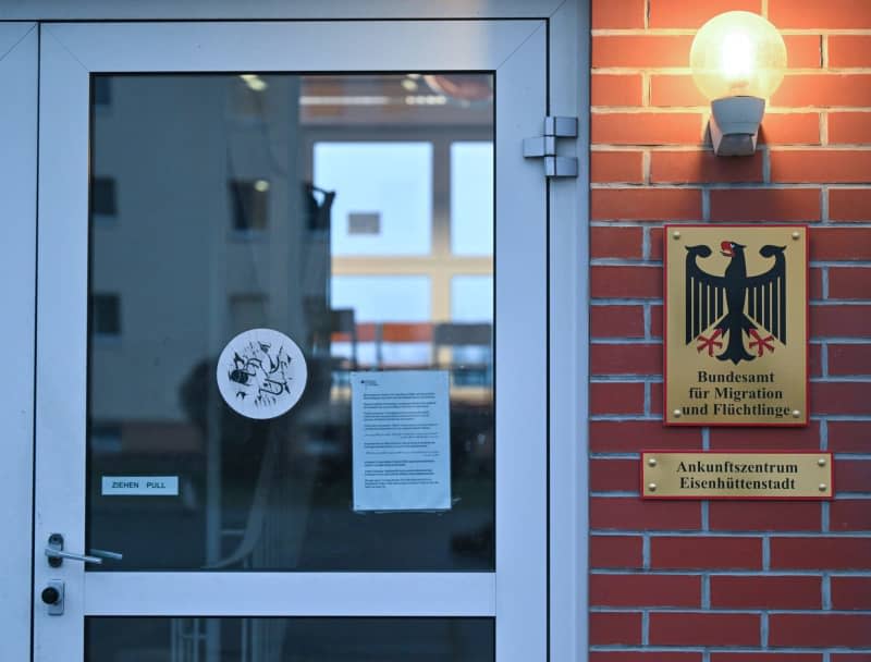 Signs from the Federal Office for Migration and Refugees at the Eisenhuettenstadt arrival center are attached to a building of the Central Initial Reception Center for Asylum Seekers (ZABH) of the state of Brandenburg. Patrick Pleul/dpa