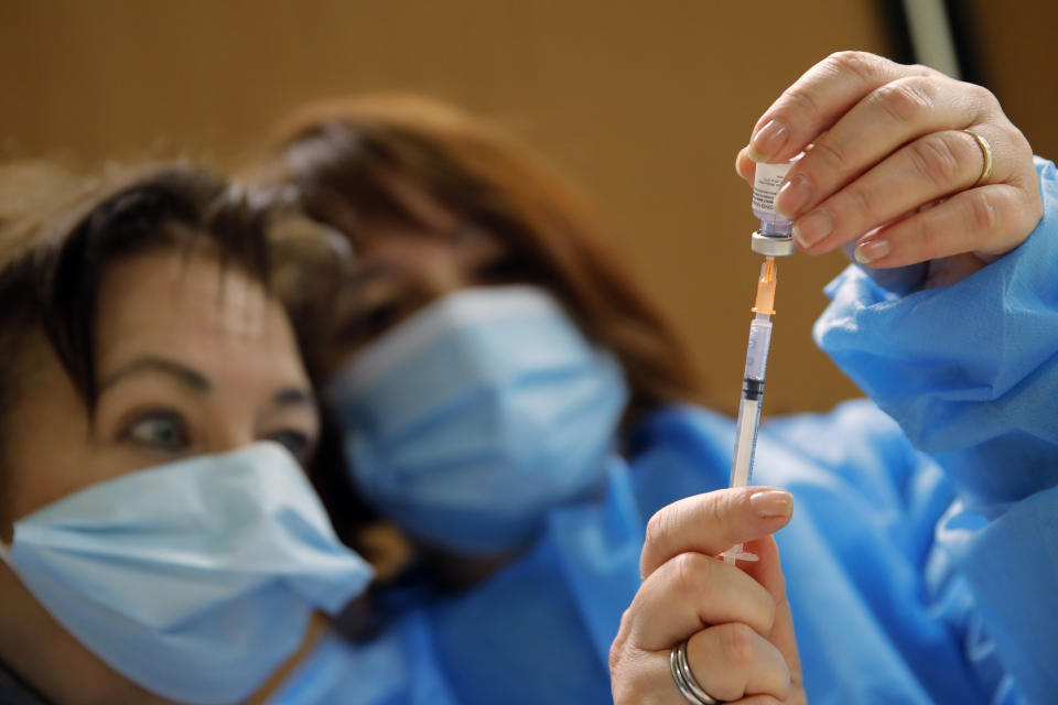 Nurses, Ines, left, and Valerie prepare a Pfizer-BioNTech COVID-19 vaccine to be administered to a health care worker at a coronavirus vaccine center in Poissy, France, Friday, Jan.8, 2021. As France examines why its vaccination campaign has started so slowly, the answer lies partly in thick forests of red tape and the government's decision to start with the toughest group to reach: the elderly in nursing homes. (AP Photo/Christophe Ena)