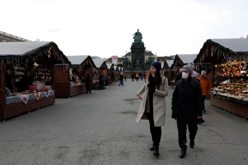 People walk over a nearly deserted Christmas market in Vienna, Austria, on Nov. 19, 2021.