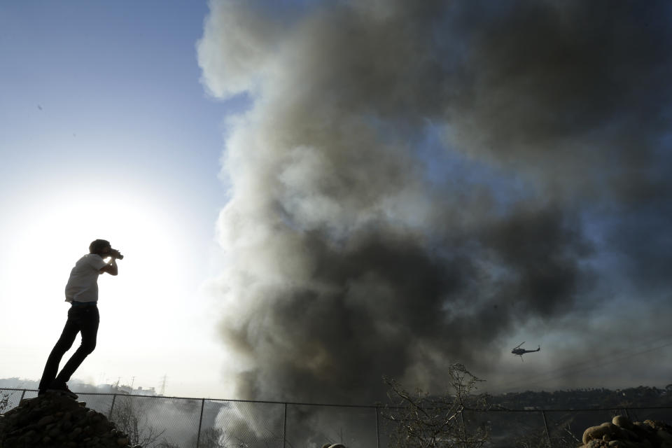 Travis Lowell takes a picture as smoke from wildfires rise, Wednesday, May 14, 2014, in Carlsbad, Calif. More wildfires broke out Wednesday in San Diego County — threatening homes in Carlsbad and forcing the evacuations of military housing and an elementary school at Camp Pendleton — as Southern California is in the grip of a heat wave. (AP Photo)