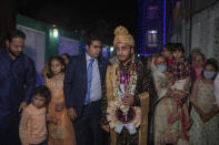 Relatives and neighbors walk along with Haseeb Mushtaq, a Kashmiri groom during his wedding ceremony on the outskirts of Srinagar, Indian controlled Kashmir, Monday, Sept. 14, 2020. The coronavirus pandemic has changed the way people celebrate weddings in Kashmir. The traditional week-long feasting , elaborate rituals and huge gatherings have given way to muted ceremonies with a limited number of close relatives attending. With restrictions in place and many weddings cancelled, the traditional wedding chefs have little or no work. The virus has drastically impacted the life and businesses in the region. (AP Photo/ Dar Yasin)