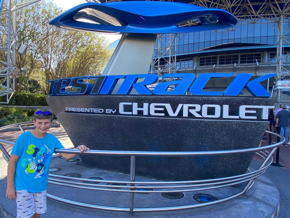 kari's son posing in front of the test track sign at epcot in disney world