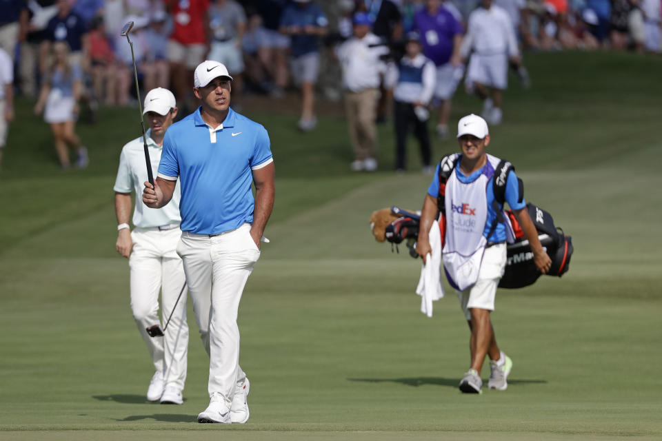 Brooks Koepka, center, and Rory McIlroy, left, of Northern Ireland, walk down the 18th fairway during the final round of the World Golf Championships-FedEx St. Jude Invitational Sunday, July 28, 2019, in Memphis, Tenn. Koepka won the tournament. (AP Photo/Mark Humphrey)