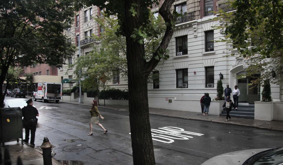 A police officer, left, stands across the street from where people gather at the entrance of a shelter on 95th Street on Friday, Sept. 28, 2012 in New York. Neighborhood residents are in turmoil, saying they were blindsided by the suddenness of the shelter's opening, a short walk from P.S. 75 on the same block. (AP Photo/Bebeto Matthews)