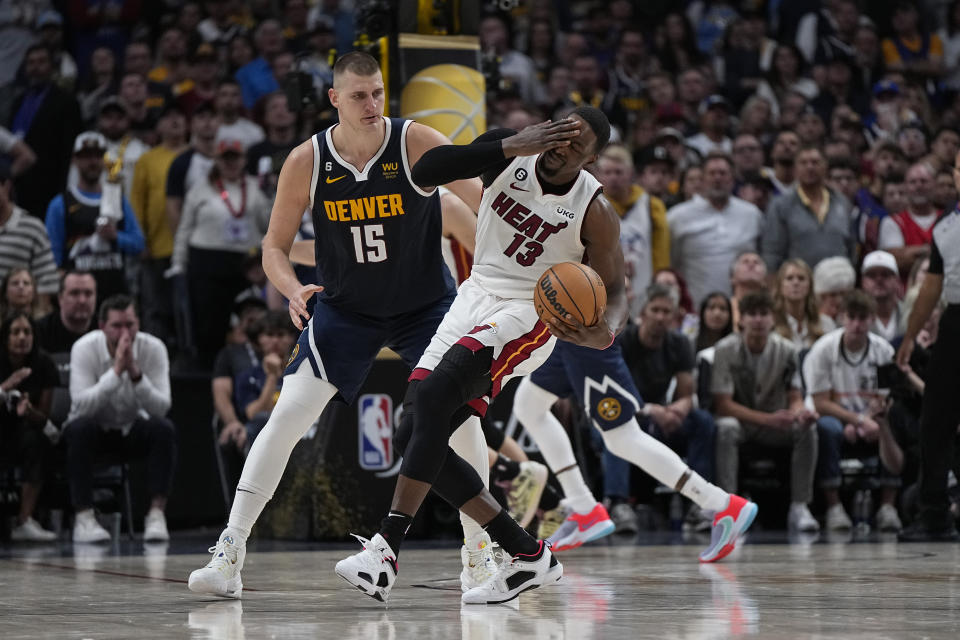 Miami Heat center Bam Adebayo (13) reacts next to Denver Nuggets center Nikola Jokic (15) during the second half of Game 2 of basketball's NBA Finals, Sunday, June 4, 2023, in Denver. (AP Photo/Mark J. Terrill)