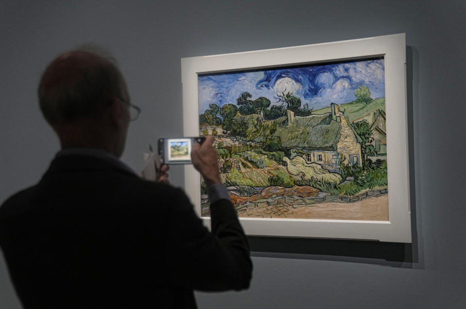 Un hombre fotografía el óleo sobre lienzo de Vincent Van Gogh "Cabañas con techo de paja de Cordeville en Auvers-sur-Oise", (1890), en la exposición "Van Gogh en Auvers-sur-Oise: Los últimos meses" en el Museo de Orsay en París, viernes 29 de septiembre de 2023. La exposición se abre al público del 3 de octubre de 2023 al 4 de febrero de 2024 y se centra en los dos meses previos a su muerte a los 37 años el 29 de julio de 1890. (Foto AP/Michel Euler)