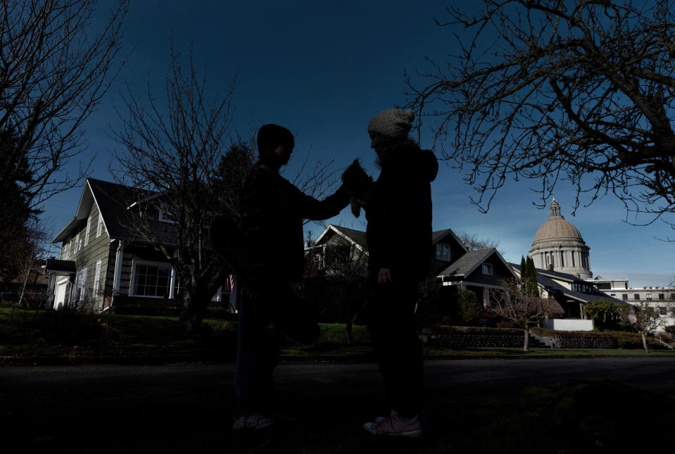 A person who lives in a neighborhood near the Capitol in Olympia, Wash., but did not want to be identified due to concerns over her family's safety, pauses while walking her dog with her son, Tuesday, Jan. 19, 2021, with the Legislative Building in the background. The normally quiet streets around the Capitol campus in Olympia have seen increased traffic and even active protesters and counterprotesters during the months leading up to Inauguration Day on Wednesday. (AP Photo/Ted S. Warren)