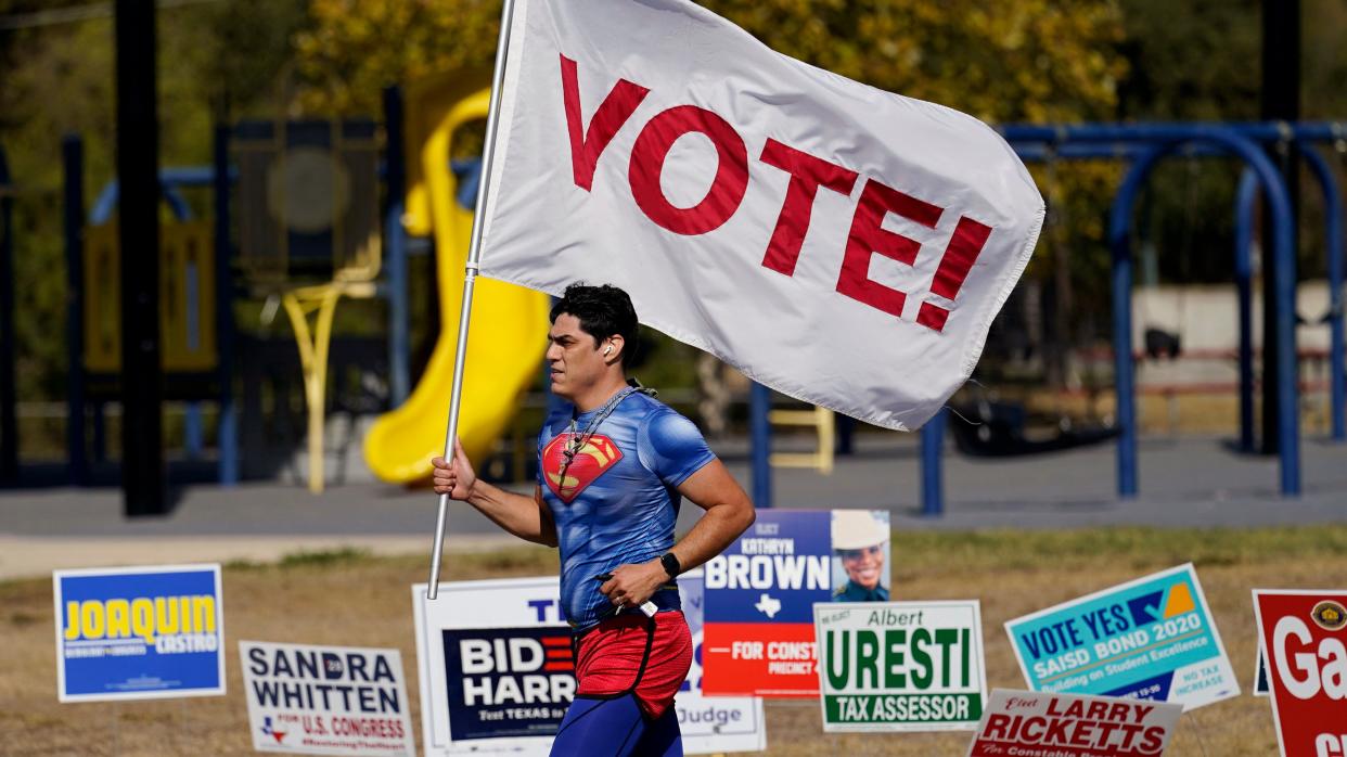 A jogger carries a "Vote" flag as he passes a polling station, Tuesday, Nov. 3, in San Antonio. (Photo: Eric Gay/AP)