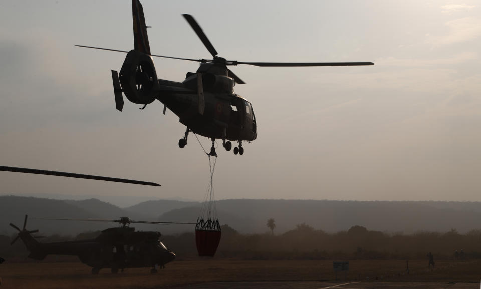 A helicopter lifts off from a military airport Robore, Bolivia, with water to drop on the Chiquitanía Forest as the military fights forest fires, Sunday, Aug. 25, 2019. Bolivian President Evo Morales said Saturday he would welcome aid in fighting his country's wildfires, which have scorched more than 2,900 square miles (744,000 hectares) of land in the Chiquitanía region over the past two weeks. (AP Photo/Juan Karita)