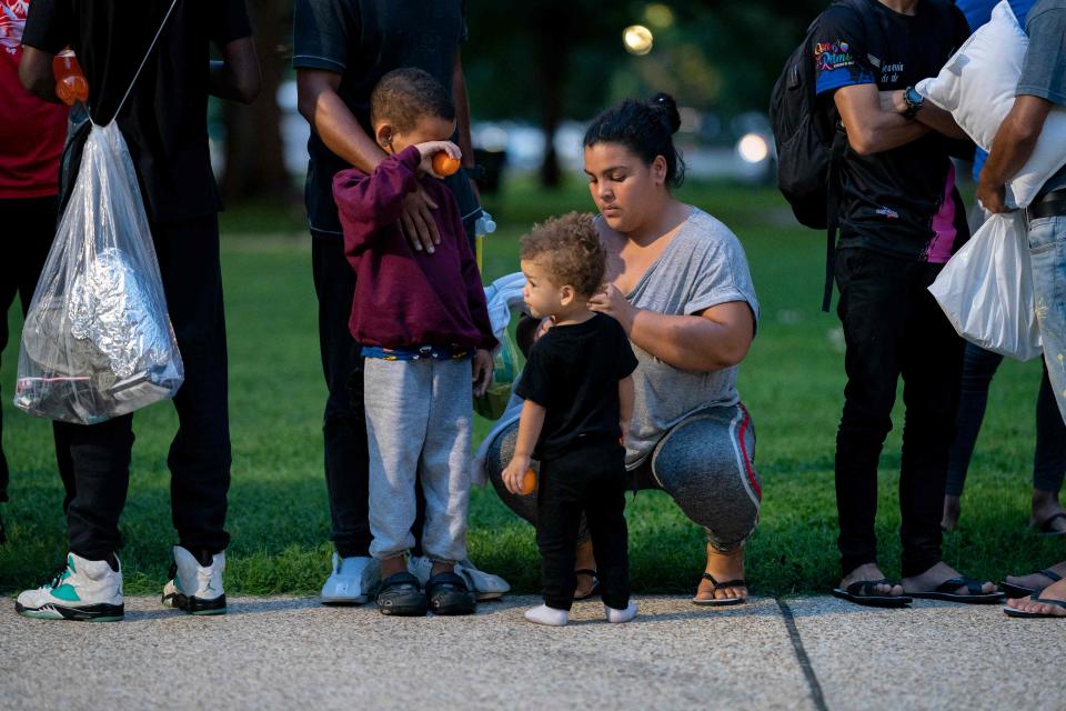 A woman who boarded a bus for migrants in Texas helps a child after being dropped off within view of the US Capitol building in Washington, DC, on Aug. 11, 2022. - Since April, Texas Governor Greg Abbott has ordered buses to carry thousands of migrants from Texas to Washington, DC, and New York City to highlight criticisms of US President Joe Biden's border policy.