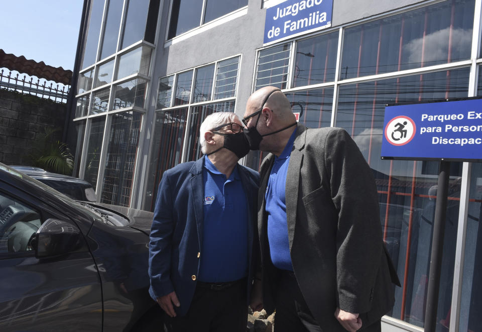 Gay equality activist Marco Castillo, left, and his longtime partner Rodrigo Campos, both wearing protective face masks, kiss in front of the cameras after they were married before a judge, in San Jose, Costa Rica, Tuesday, May 26, 2020. Costa Rica became the latest country to legalize same-sex marriage early Tuesday when a ruling from its supreme court went into effect ending the country's ban. (AP Photo/Carlos Gonzalez)