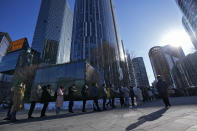 People wearing face masks to help protect from the coronavirus line up to get a throat swab at a coronavirus test site setup near a commercial office complex in Beijing, Tuesday, Jan. 25, 2022. Hong Kong has already suspended many overseas flights and requires arrivals be quarantined, similar to mainland China's "zero-tolerance" approach to the virus that has placed millions under lockdowns and mandates mask wearing, rigorous case tracing and mass testing. (AP Photo/Andy Wong)