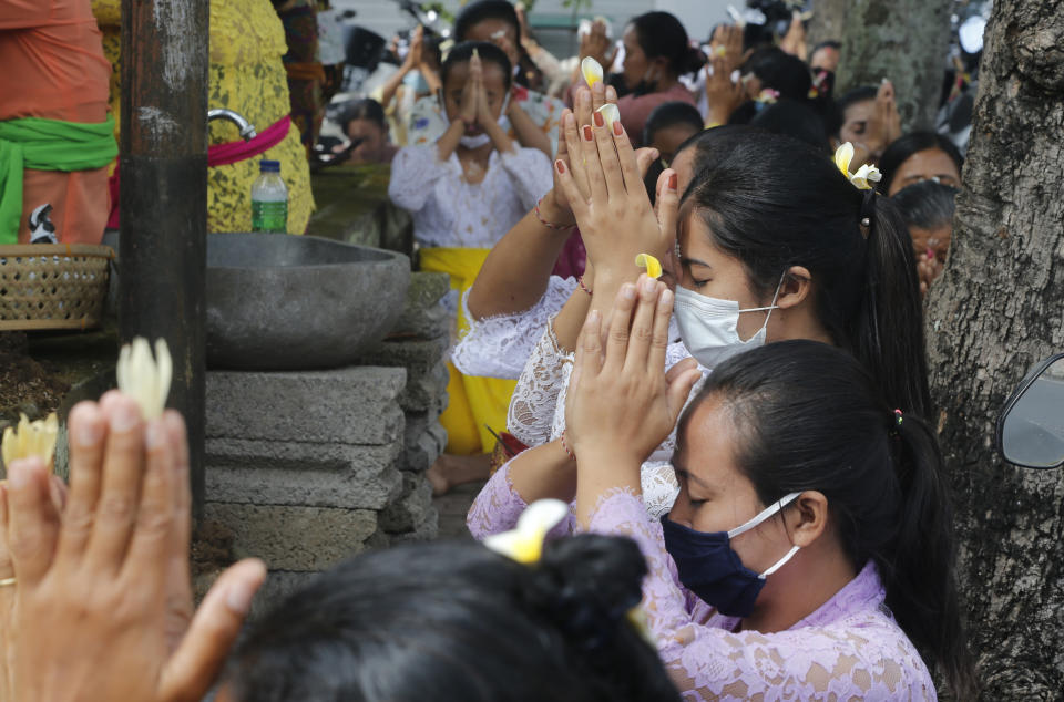 Women wearing face masks as a precaution against the new coronavirus outbreak pray during a Hindu ritual prayer at a temple in Bali, Indonesia, Wednesday, Sept. 16, 2020. (AP Photo/Firdia Lisnawati)