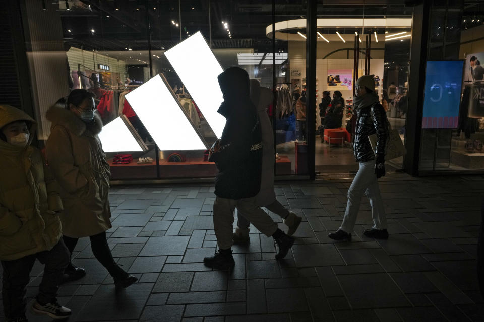 Shoppers walk by an Adidas Store at an outdoor shopping mall in Beijing on Saturday, Dec. 23, 2023. It was tumultuous 2023 for the Chinese economy. Some of the world's biggest brands said they were weighing, or already have decided, to shift manufacturing away from China amid unease about security controls, government protection of their Chinese rivals and Beijing's wobbly relations with Washington. But there was at least one bright spot for Beijing amid all the tough news about declining foreign investment: American fast food companies have announced a surge of investment in a market of 1.4 billion people. KFC, McDonald's and Starbucks are among companies in recent months that have announced plans for major investment in China. (AP Photo/Andy Wong)