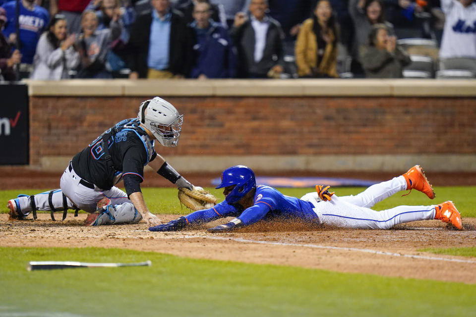 New York Mets' Francisco Lindor, right, slides past Miami Marlins catcher Jacob Stallings to score on a walk-off single by Eduardo Escobar during the 10th inning of a baseball game Wednesday, Sept. 28, 2022, in New York. The Mets won 5-4. (AP Photo/Frank Franklin II)