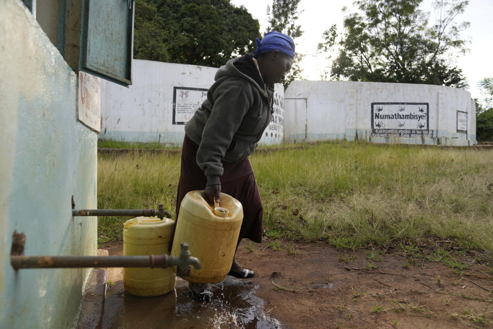 Joyce Mule llena garrafas de agua en un depósito, en el condado de Makueni, Kenia, el 29 de febrero de 2024. Los aldeanos construyeron un muro de concreto alrededor de la roca para atrapar el agua de la lluvia. Colocan grandes piedras para filtrarla y una tubería para bajarla hasta los depósitos de almacenamiento. (AP Foto/Brian Inganga)