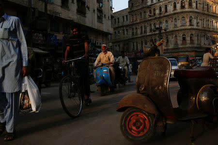 A man rides a Vespa scooter on a busy street, in a low-income neighbourhood in Karachi, Pakistan March 6, 2018. REUTERS/Akhtar Soomro