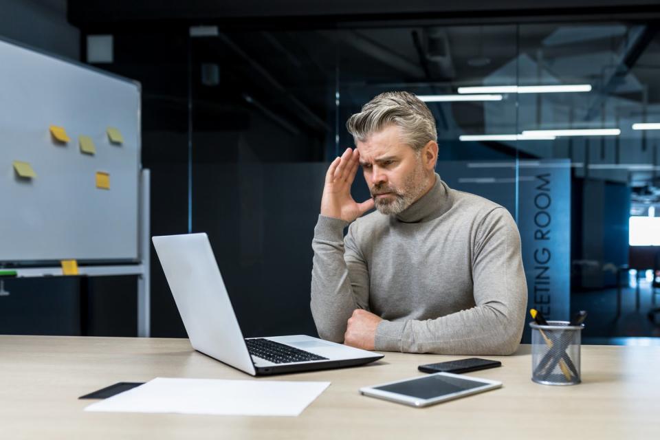 Concerned person looking at laptop in office.