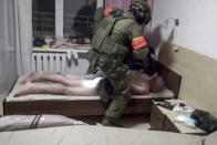 In this photo taken from video released by Belarusian KGB, State TV and Radio Company of Belarus on Wednesday, July 29, 2020, a Belarusian KGB officer detains a Russian man in a sanitarium outside in Minsk, Belarus. Belarusian officials said that more than 30 detained employees of private Russian military contractor Wagner are facing a criminal probe on charges of plotting terror attacks in Belarus amid a presidential election campaign. (Belarusian KGB, State TV and Radio Company of Belarus via AP)