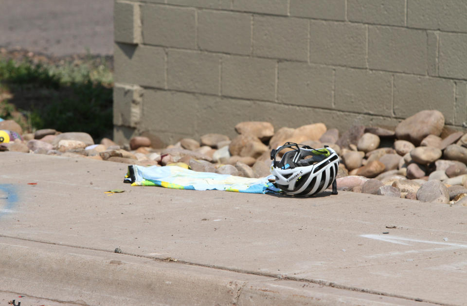 In this Saturday, June 19, 2021, photo courtesy of The White Mountain Independent is a cyclist's helmet at the scene of an accident in Show Low, Ariz. A driver in a pickup truck plowed into bicyclists competing in a community road race in Arizona on Saturday, critically injuring several riders before police chased down the driver and shot him outside a nearby hardware store, police said. (Jim Headley/The White Mountain Independent via AP)