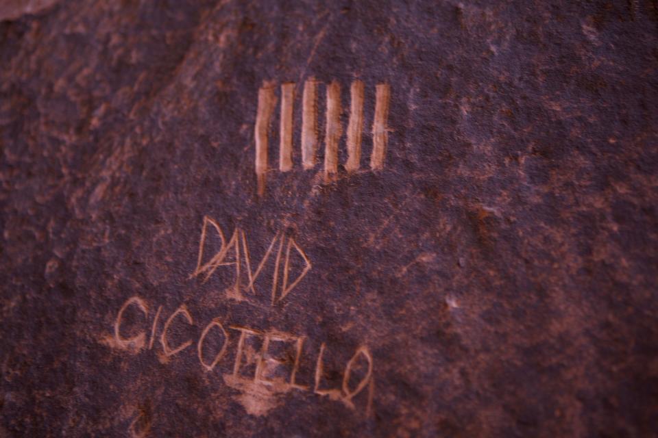 David Cicotello's carving, made about 8 feet to the left of the rappel line, marked the days that passed as he waited for rescue in No Mans Canyon, Utah. Steven D. Kugath,  a faculty member in the Recreation Management Program here at Brigham Young University Idaho, found them on a canyoneering trip as he paused to shoot photos of the beautiful scenery overhead. "This area is mostly enclosed by steep rock walls," he says, "creating a Cathedral-like effect."