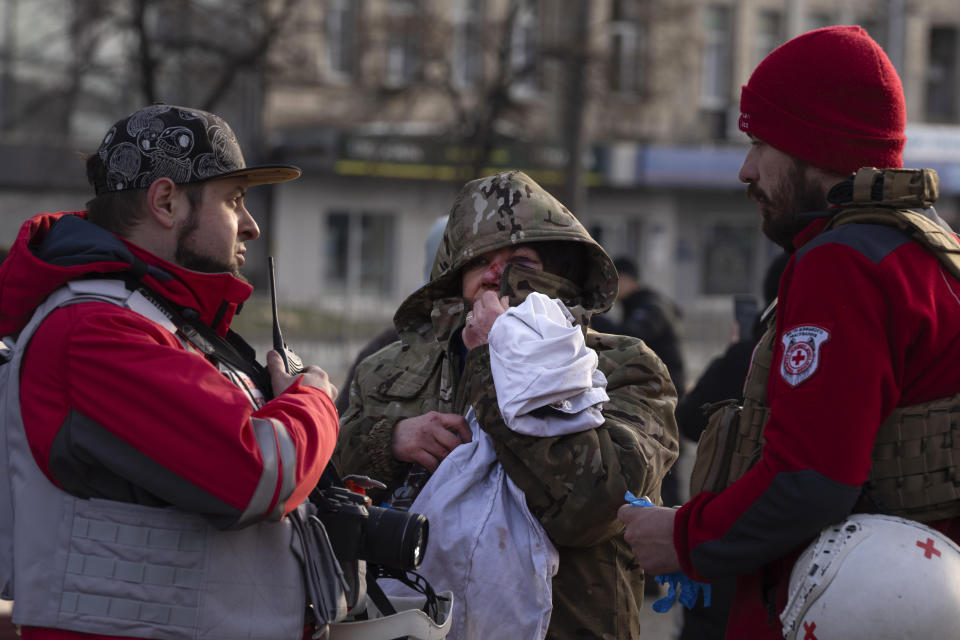 A wounded resident talks with paramedics after Russia's missile attack in Kyiv, Ukraine, Friday, Dec. 29, 2023. Russia launched about 110 missiles as well as drones against Ukrainian targets during the night Ukraine President Volodymyr Zelenskyy said Friday, in what appeared to be one of the biggest aerial barrages of the 22-month war.(AP Photo/Efrem Lukatsky)