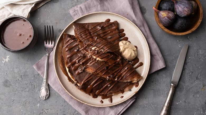 plate of chocolate crepes with chocolate sauce and whipped cream