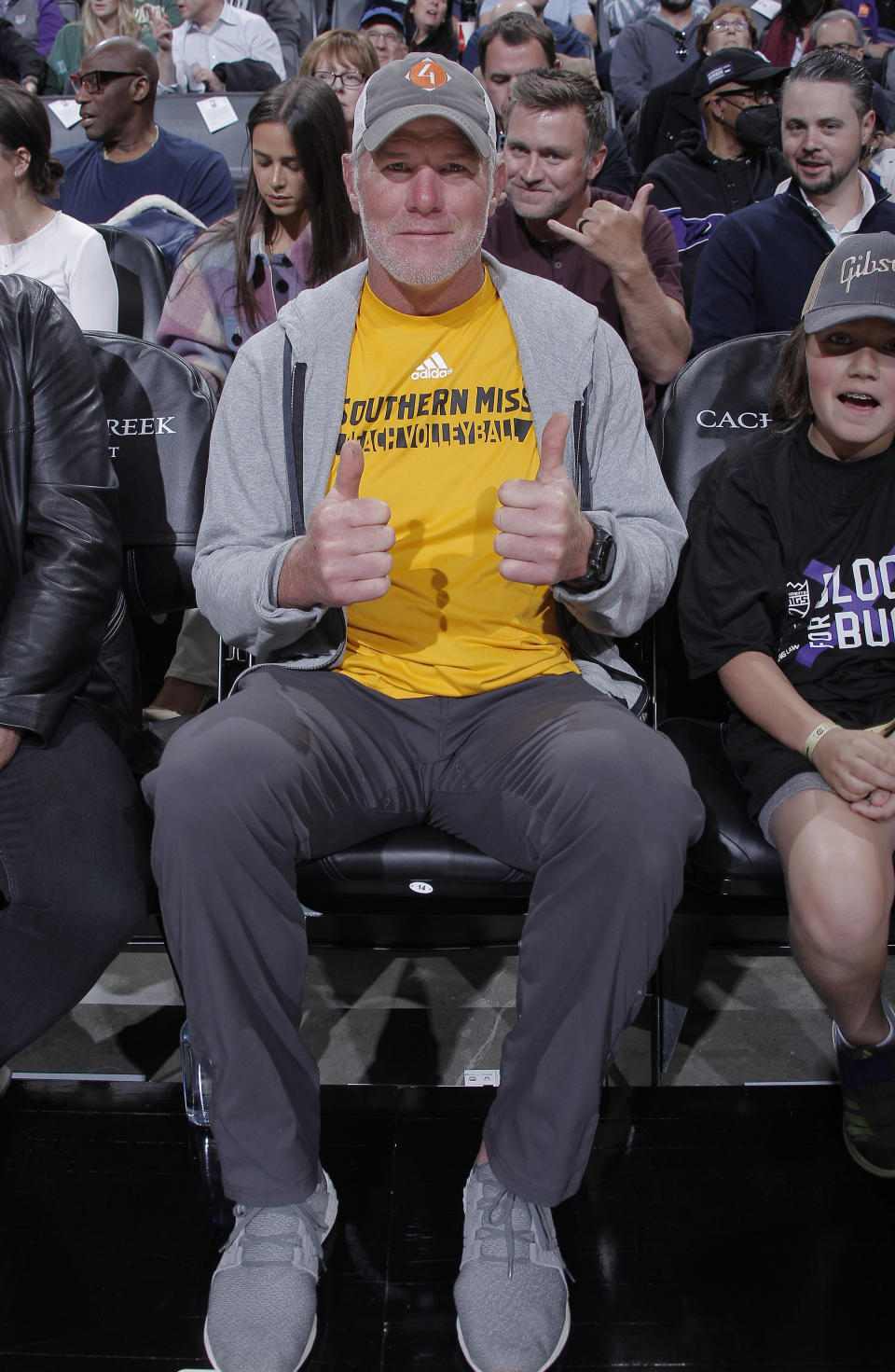 Man in a Southern Miss t-shirt and cap sitting with thumbs up at an event