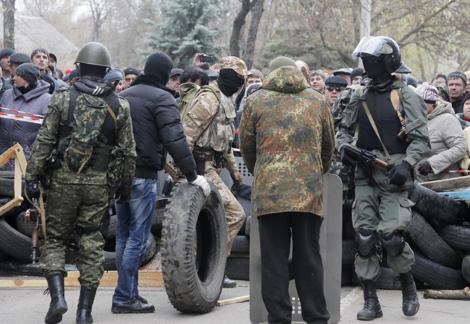 Armed pro-Russian activists occupy the police station and build a barricade as people watch on, in the eastern Ukrainian town of Slovyansk on Saturday, April 12, 2014. Pro-Moscow protesters have seized a number of government buildings in the east over the past week, undermining the authority of the interim government in the capital, Kiev. (AP Photo/Efrem Lukatsky)