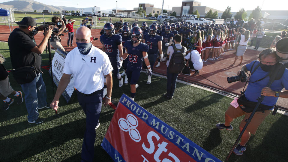 Herriman players take the field for a high school football game against Davis on Thursday, Aug. 13, 2020, in Herriman, Utah. Utah is among the states going forward with high school football this fall despite concerns about the ongoing COVID-19 pandemic that led other states and many college football conferences to postpone games in hopes of instead playing in the spring. (AP Photo/Rick Bowmer)