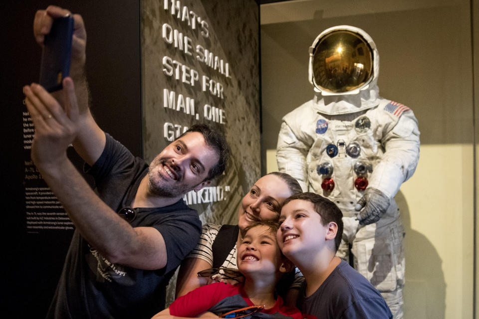 Rafiel Santos and Silvia Freddo, and their two children Jose Eduardo, 11, right, and Gustavo, 6, bottom, of Santa Catarina, Brazil, take a selfie as some of the first visitors to view Neil Armstrong's Apollo 11 spacesuit after it is unveiled at the Smithsonian's National Air and Space Museum on the National Mall in Washington, Tuesday, July 16, 2019. (AP Photo/Andrew Harnik)