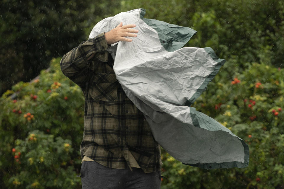 A tourist struggles with his rain poncho in strong wind as weather associated with Storm Lee hits the region, Saturday, Sept. 16, 2023, in Bar Harbor, Maine. Severe conditions were predicted across parts of Massachusetts and Maine, and hurricane conditions could hit the Canadian provinces of New Brunswick and Nova Scotia, where the storm, Lee, downgraded early Saturday from hurricane to post-tropical cyclone, was expected to make landfall later in the day. (AP Photo/Robert F. Bukaty)