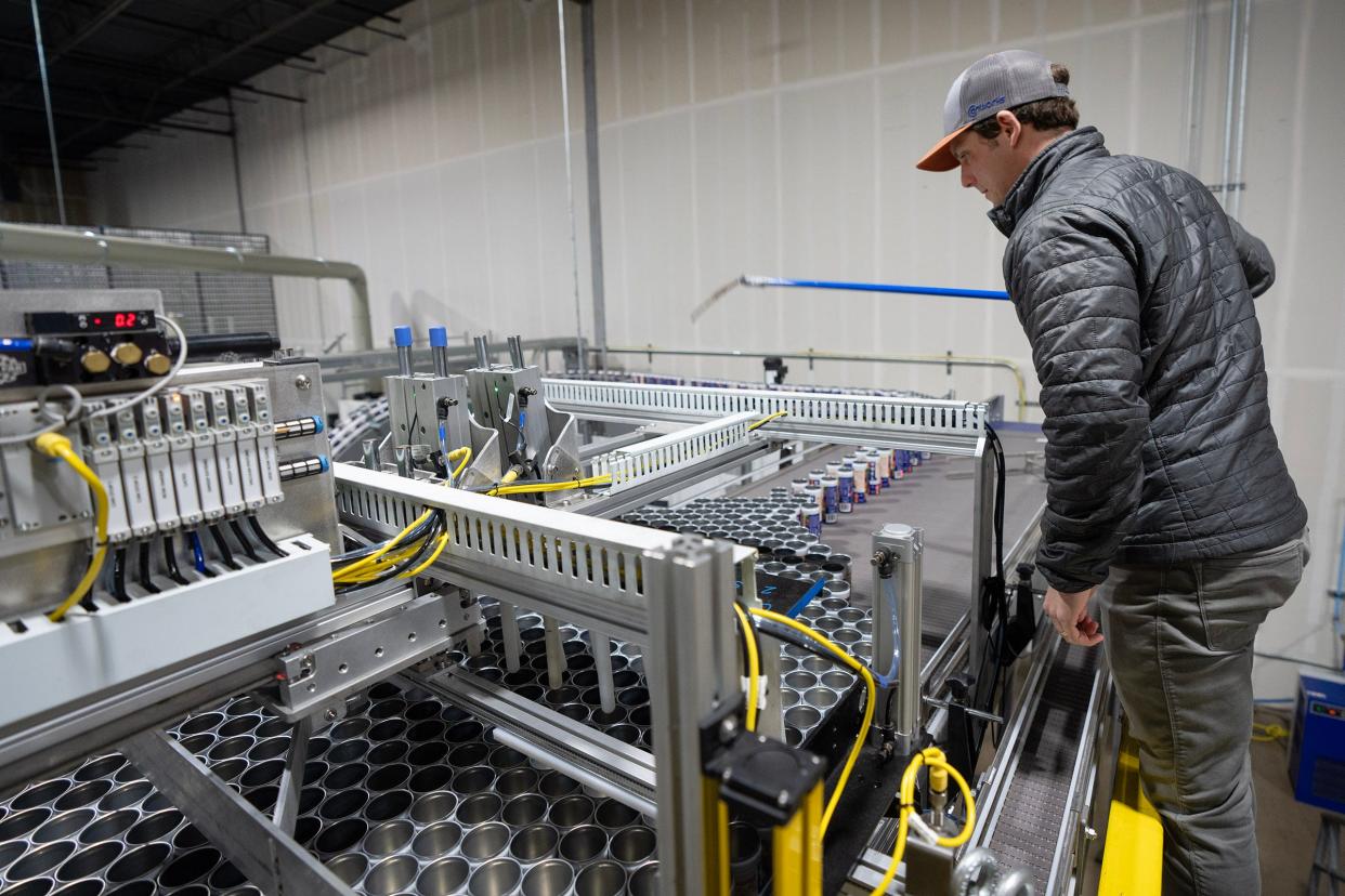 Co-owner Marshall Thompson oversees operations as a machine groups together freshly-printed aluminum cans at the warehouse at Canworks Wednesday, Jan. 16, 2024. The facility prints branding artwork onto thousands of aluminum cans a day, helping businesses across the country.