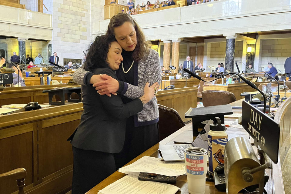 From left, Nebraska Sens. Jen Day and Danielle Conrad hug on the floor of the Nebraska Legislature during emotional debate of a bill that would ban gender-affirming care for anyone 18 and younger in the state on Thursday, March 23, 2023 in Lincoln, Neb. The contentious bill advanced Thursday, despite a threat by several lawmakers, including Day and Conrad, to filibuster the rest of the session if it moved forward. (AP Photo/Margery Beck)