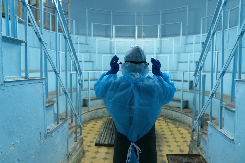 Olena Mazur, pathologist wearing special suits to protect herself against coronavirus, prepares to conduct an autopsy in an anatomical theater at the Lviv National Medical University in Lviv, Western Ukraine, on Tuesday, Jan. 5, 2021. A medical college in western Ukraine has been transformed into a temporary hospital as the coronavirus inundates the Eastern European country. (AP Photo/Evgeniy Maloletka)