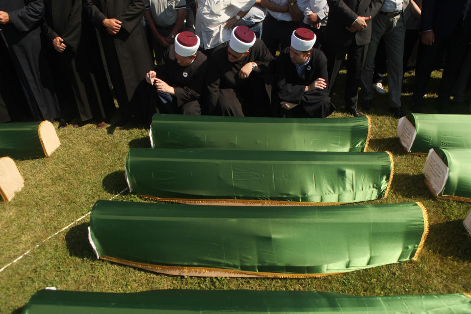 Relatives and friends of the victims, with religious leaders among the some thousands of mourners gathered at a soccer stadium in Kozarac near the town of Prijedor, behind the coffins draped with green cloth for the funeral of 86 Muslims, Saturday July 20, 2019. The victims were slain by Serbs in one of the worst atrocities of the country's 1992-95 war, aged 19 to 61, and were among some 200 Bosnian Muslims and Croats from Prijedor who were executed in Aug. 1992 on a cliff on Mt. Vlasic known as Koricanske Stijene. (AP Photo/Almir Alic)