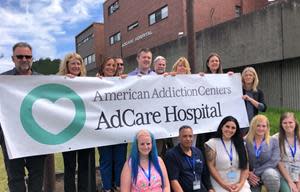 AdCare Hospital employees display banner with AdCare's new logo reflecting our core values and mission; the logo is a visual representation of the immense heart that each of our staff bring to our addiction treatment programs and our patients.