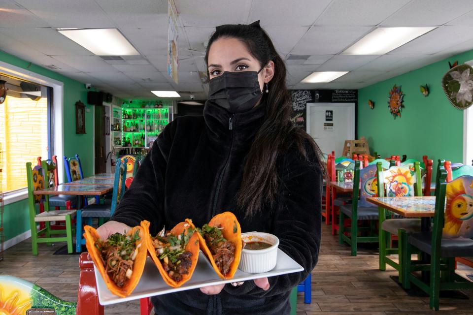 Aztec Restaurant co-owner Dulce Guerrero holds Birria tacos with a cup of consomé for dipping, at the Waverly Street restaurant, April 30, 2021.