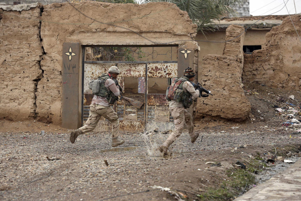 FILE - Iraqi Army soldiers secure streets in a village recently liberated from Islamic State militants outside Mosul, Iraq, Dec. 1, 2016. Ten years after the Islamic State group declared its caliphate in large parts of Iraq and Syria, the extremists now control no land, have lost many prominent founding leaders and are mostly away from the world news headlines. (AP Photo/Hadi Mizban, File)