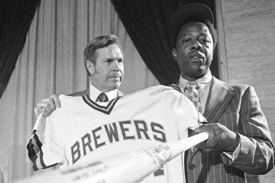 FILE - Milwaukee Brewers manager Del Crandall, left, and Henry Aaron display Aaron's new Brewers jersey and a bat during a news conference in Milwaukee to announce signing Aaron, in this Nov. 14, 1974, file photo. Crandall, a star catcher who played on two Milwaukee Braves teams that reached the World Series in the 1950s before managing the Milwaukee Brewers and Seattle Mariners, has died. He was 91. Crandall’s son Bill said his father was surrounded by family members as he died from circumstances of Parkinson’s disease Wednesday, May 5, 2021, at Mission Viejo, California.(AP Photo/Paul Shane, File)