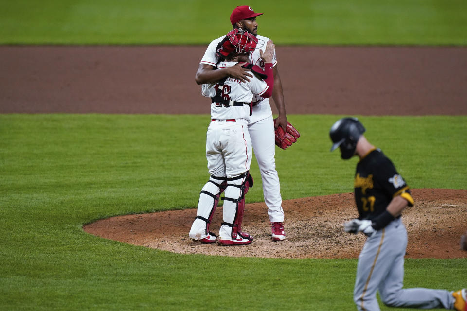 Cincinnati Reds relief pitcher Amir Garrett and catcher Tucker Barnhart (16) embrace after the Reds defeated the Pirates 4-1 in a baseball game in Cincinnati, Tuesday, Sept. 15, 2020. (AP Photo/Bryan Woolston)