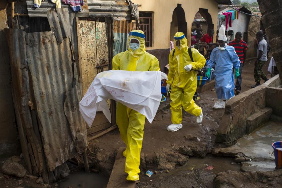 A worker carries the body of a baby, placed in a white bag, in Freetown, Sierra Leone, in 2014.