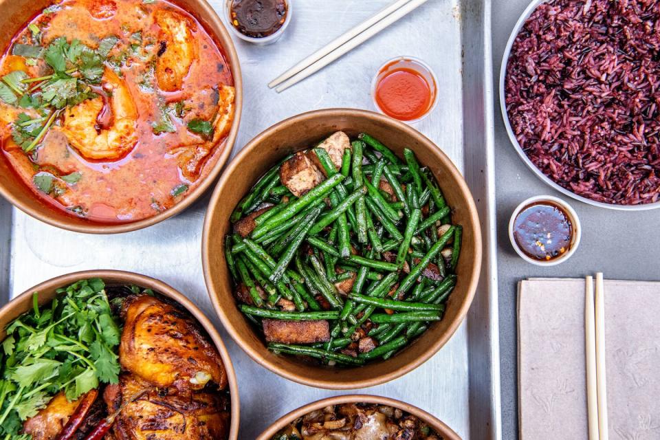 An overhead photo of a range of Thai dishes, including green beans and a red curry shrimp dish