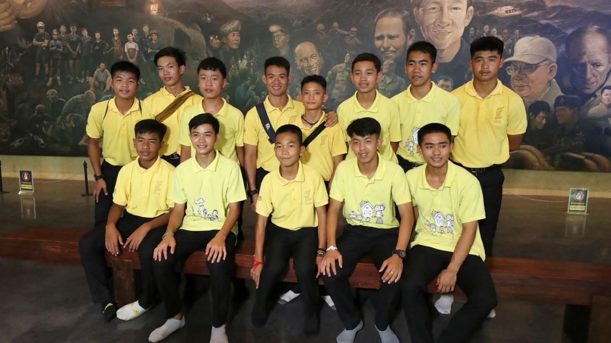 Die 12 Jungs der Fußballmannschaft der «Wildschweine» aus Mae Sai und ihr ehemalige Fußballtrainer Ekkapol Chanthawong (4.v.l, hintere Reihe), die zusammen vor drei Jahren aus der überfluteten Tham-Luang-Höhle gerettet wurden, bei einer Pressekonferenz.