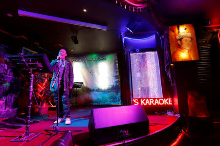 A man sings in a Karaoke bar beside a portrait of King Jigme Khesar Namgyel Wangchuck in the capital city of Thimphu, Bhutan, December 16, 2017. REUTERS/Cathal McNaughton