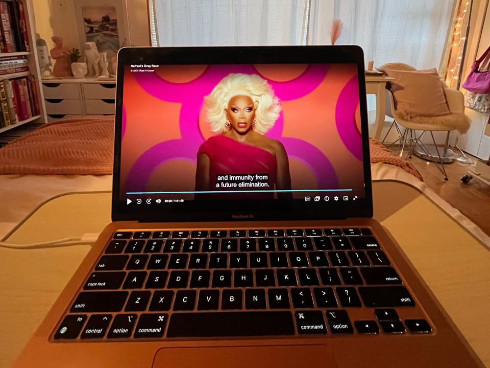 rupaul's drag race playing on a laptop screen resting on a bed in a decorated bedroom