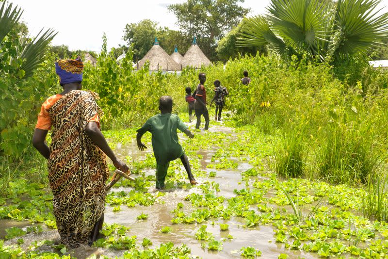 Residents wade through flood water from the broken dykes on Nile river, in Duk padiet county of Jonglei State